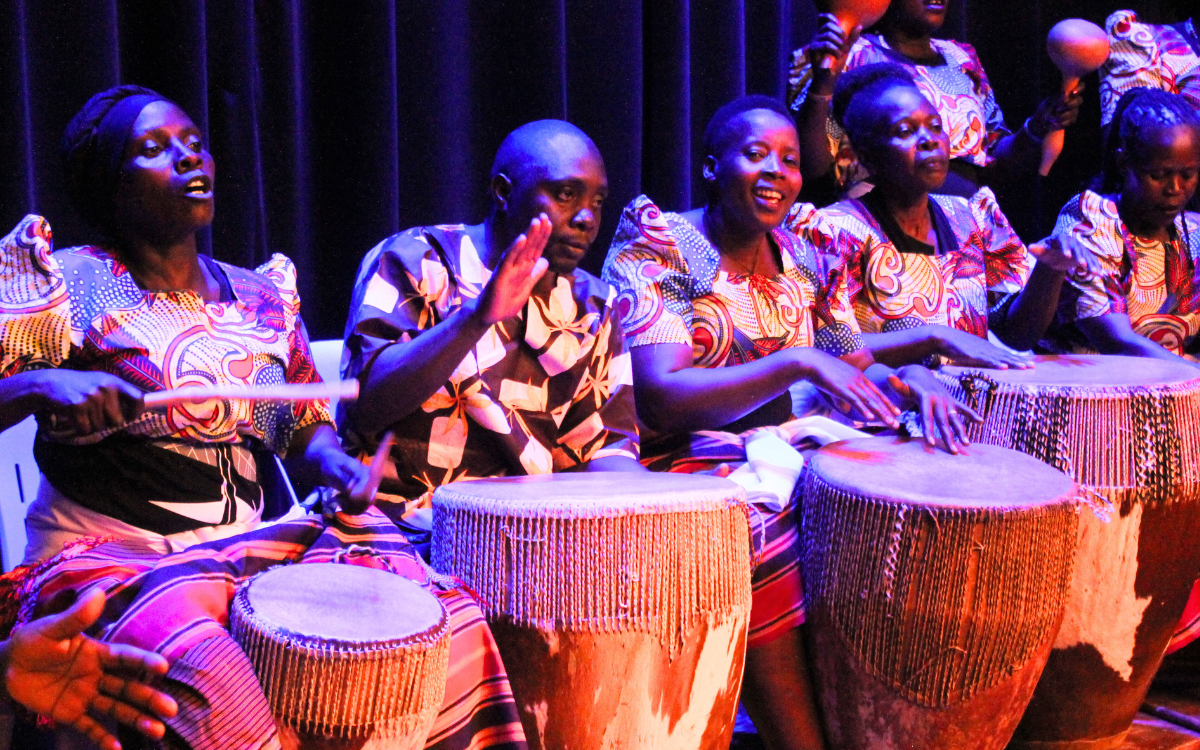 Women and men performing on drums in Uganda.